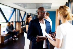 Executive standing and talking to colleague holding notepads